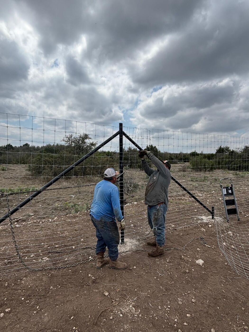 Two crew members setting a black steel corner brace assembly