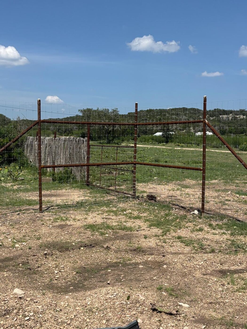 Welded pipe corner assembly with ranch gate under a blue Texas sky