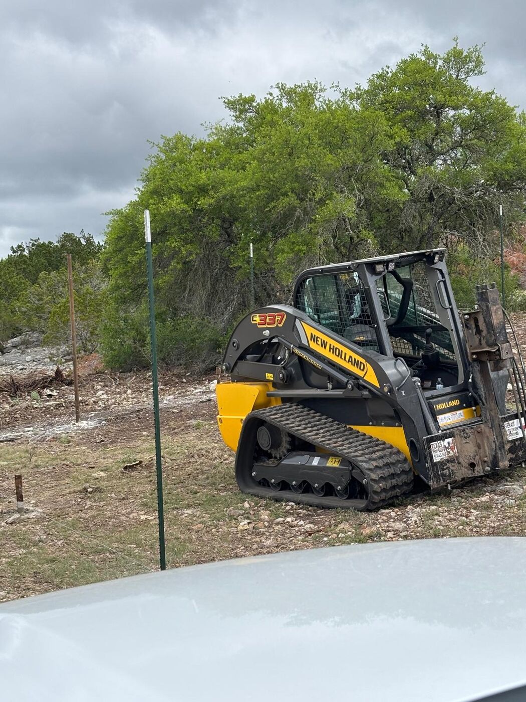 New Holland C337 track skid steer with post driver attachment on the fence line